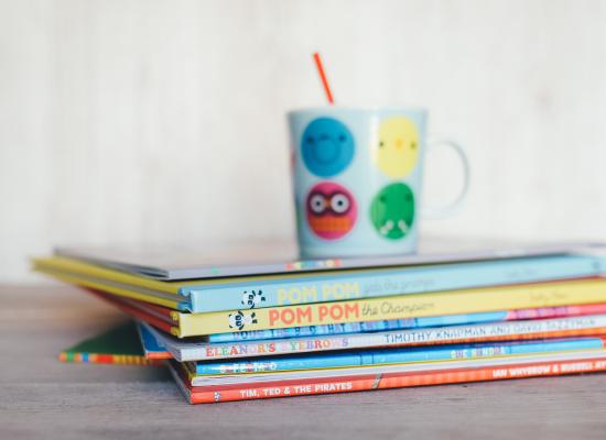 stack of childrens books and a mug